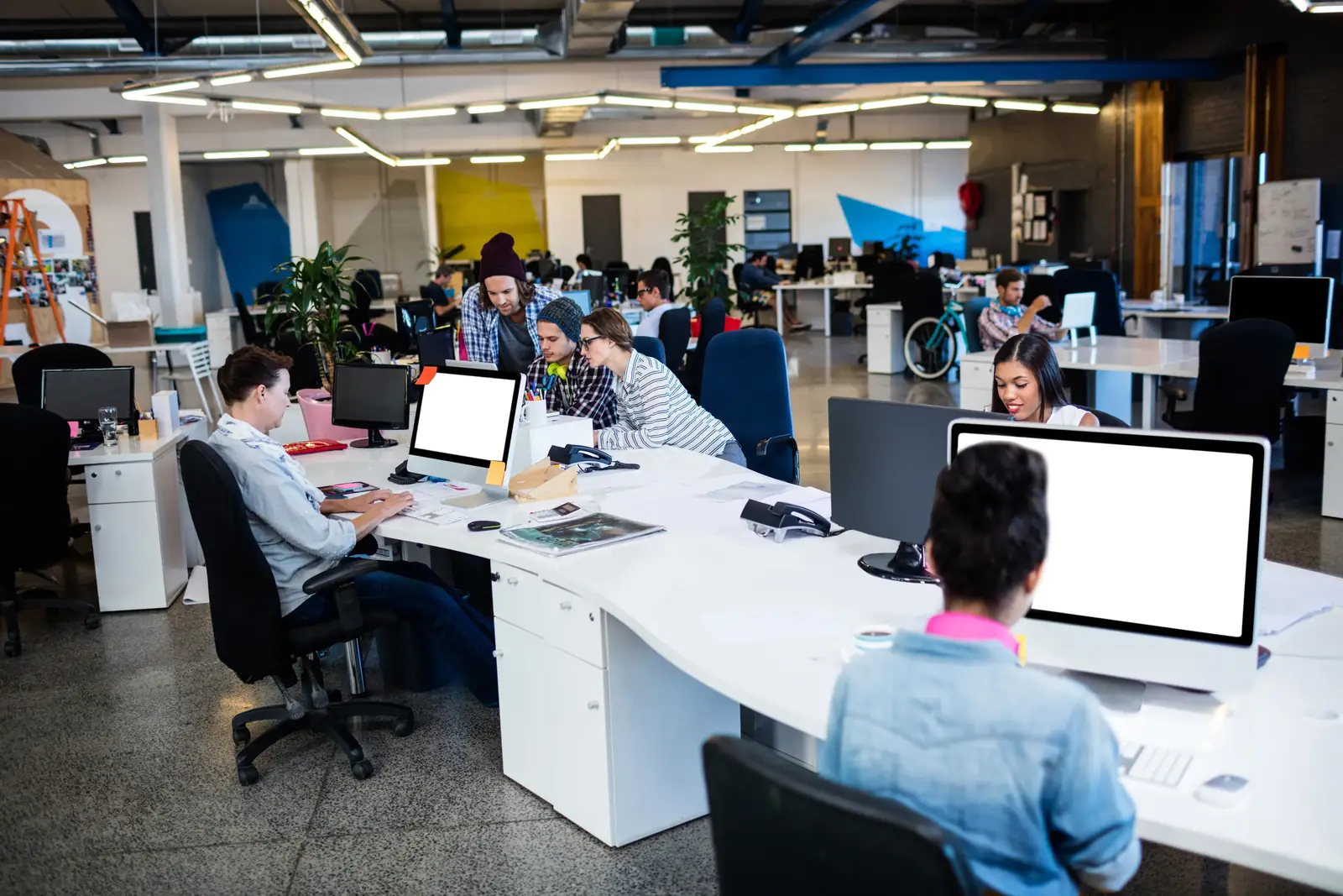 open space de bureaux où plusieurs personnes travaillent sur ordinateur