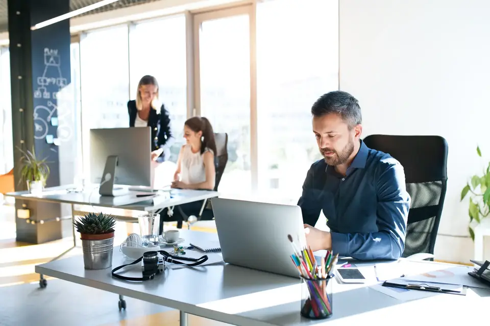 Espace de bureaux lumineux où travaillent trois personnes