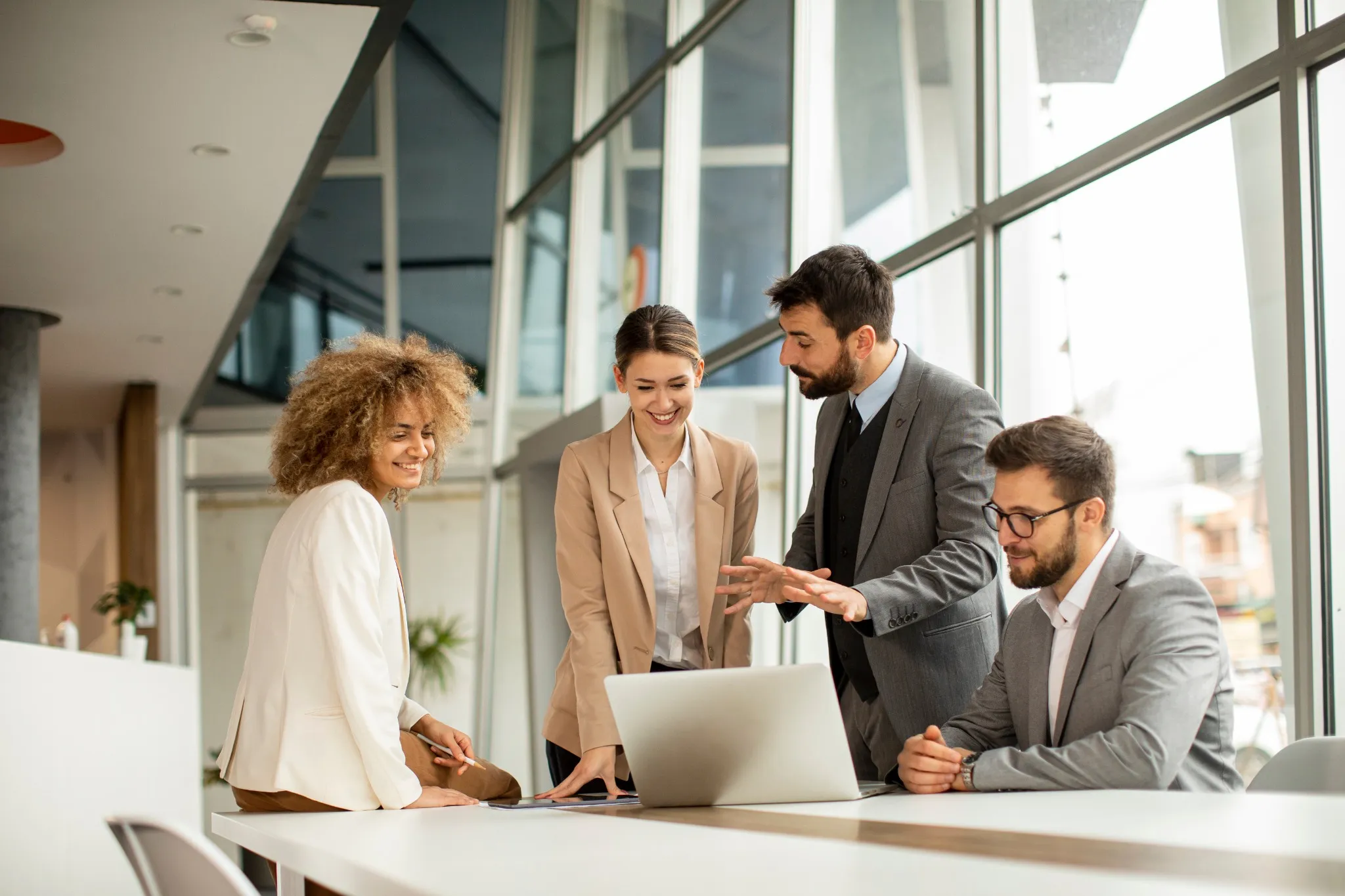 Discussion d'équipe autour d’un ordinateur dans un espace de coworking pour investir dans des bureaux